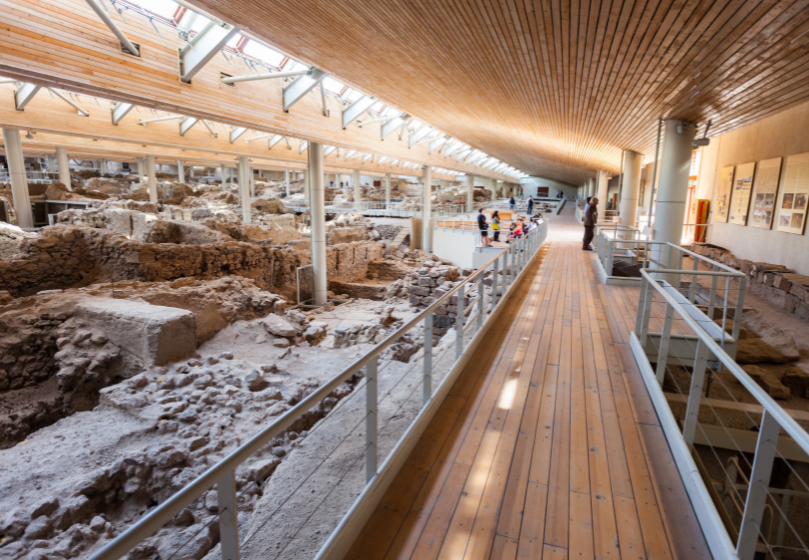 Akrotiri archeologinė vietovė su senoviniais griuvėsiais po mediniu stogu ir lankytojų taku